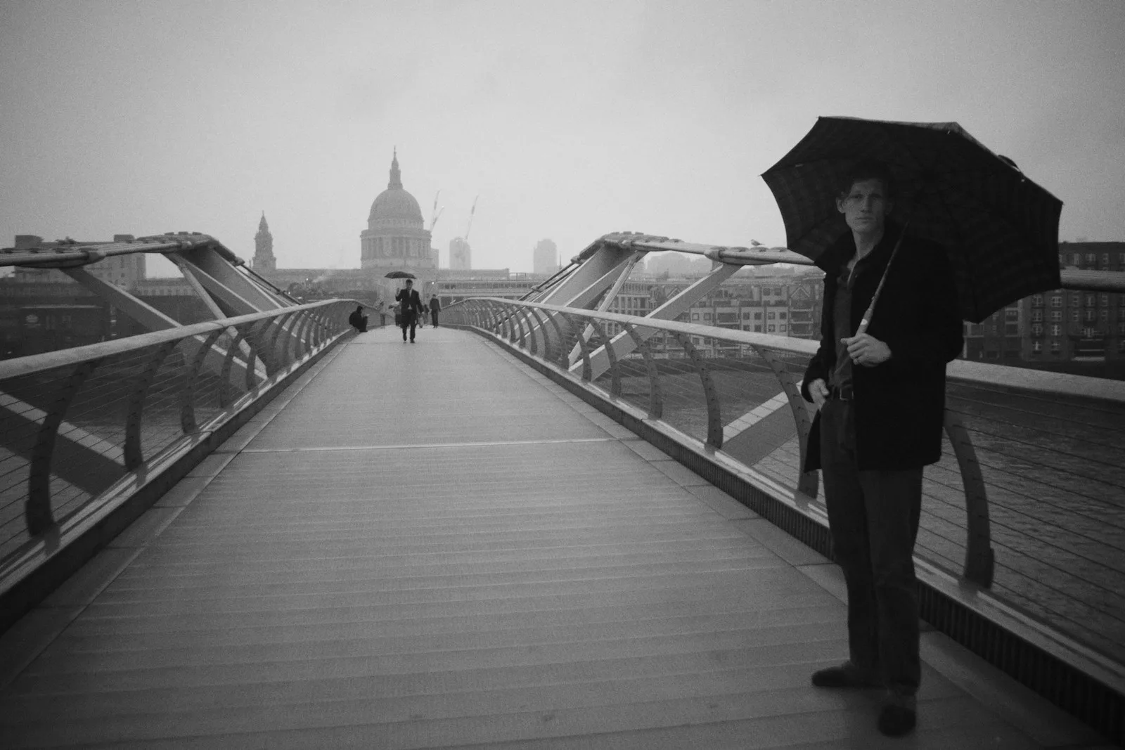 a woman standing on a bridge holding an umbrella