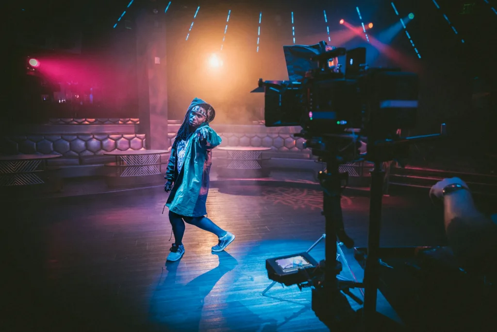 woman dancing on stage near black cameras