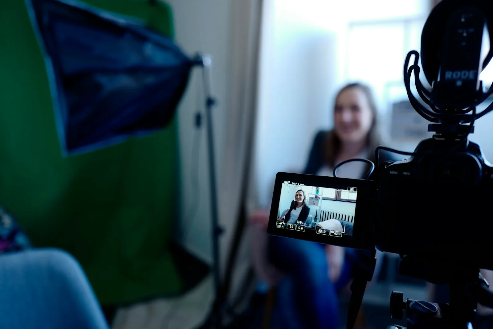 a woman sitting in front of a green screen